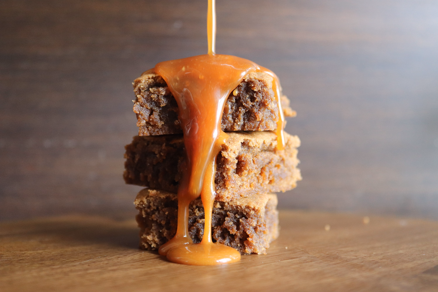 Three blondies stacked, caramel poured over the top