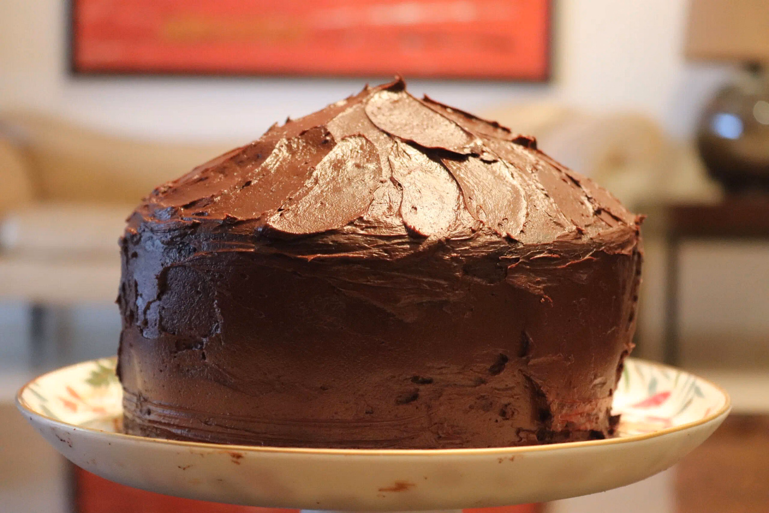 A dark chocolate layer cake with thick fudge icing, one slice cut away